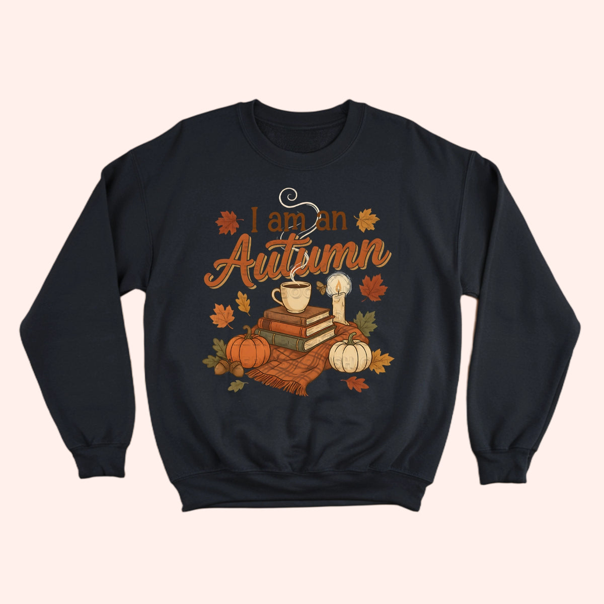 A black crewneck sweatshirt featuring a cozy autumn graphic with the text 'I am an Autumn' in orange script, surrounded by pumpkins, books, a mug, a candle, and leaves.