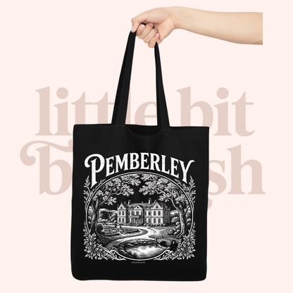 Black tote bag with 'Pemberley' design held by a hand on a light pink background.